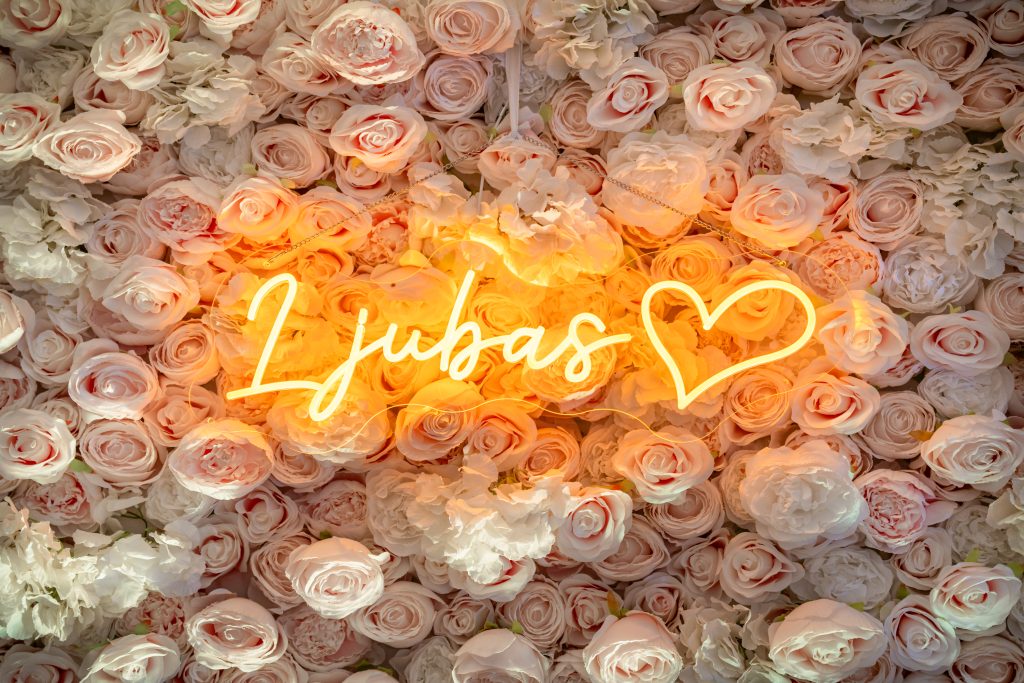 Ljubas neon natpis na zidu od ruža